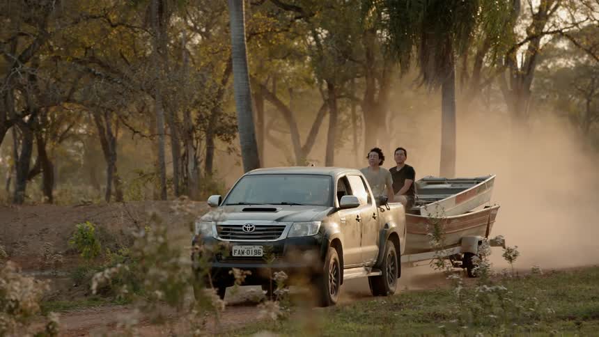 A truck pulls a boat on a dirt road