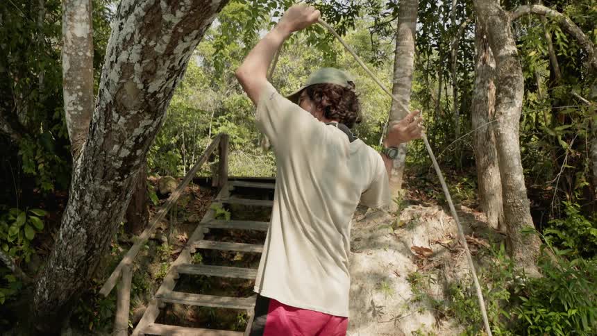 Man carries a rope through the trees