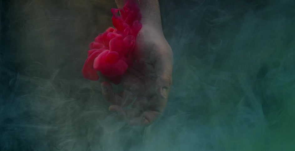 A person puts their hands in the water as ink floats around