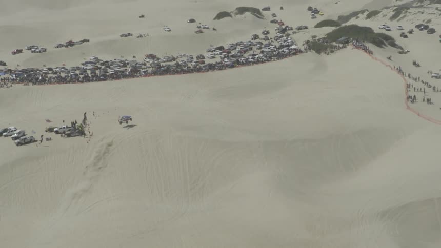 A vehicle drives off-road in the desert