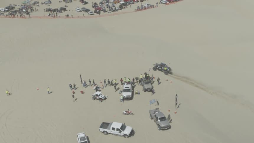 A car is driving toward people in the desert