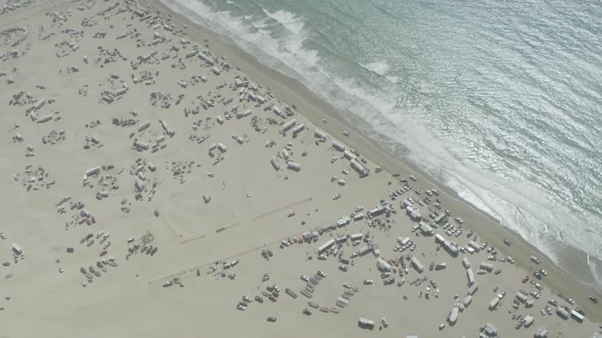 Recreational vehicles and cars drive and park on a beach