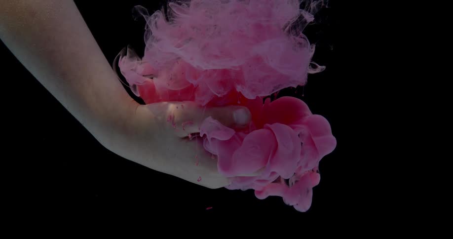 A person puts their hand in the water as red ink falls on it