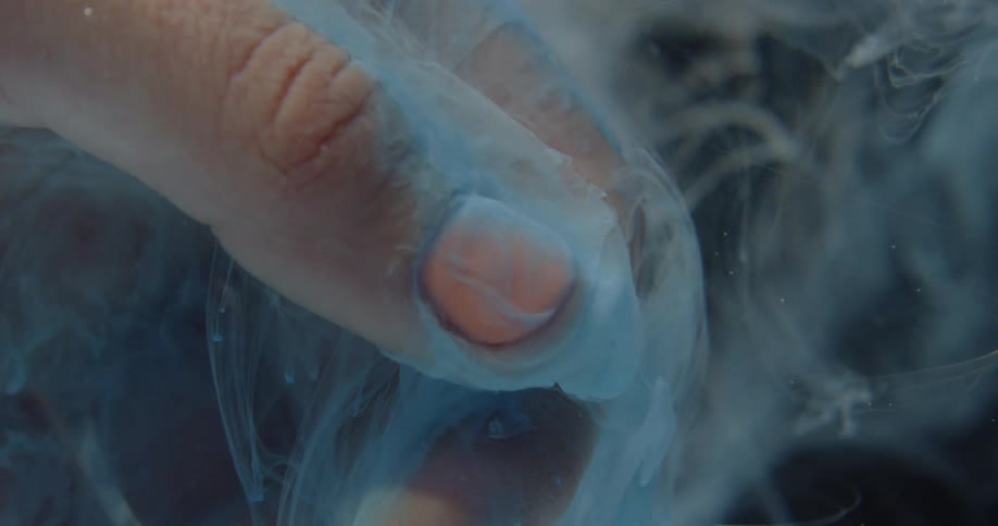 Hand submerged in water and blue liquid