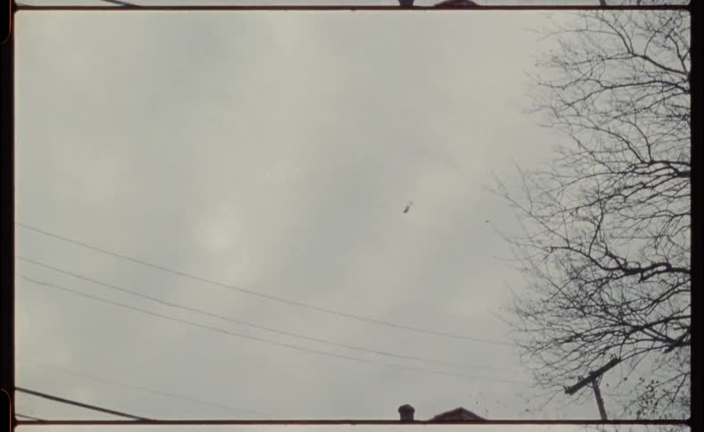 A helicopter flies in the cloudy sky above the town