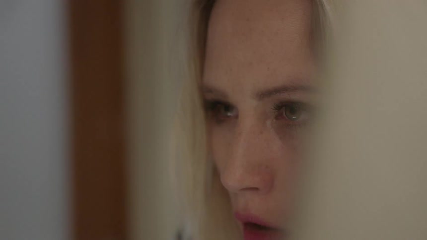 A woman stares forward while standing indoors