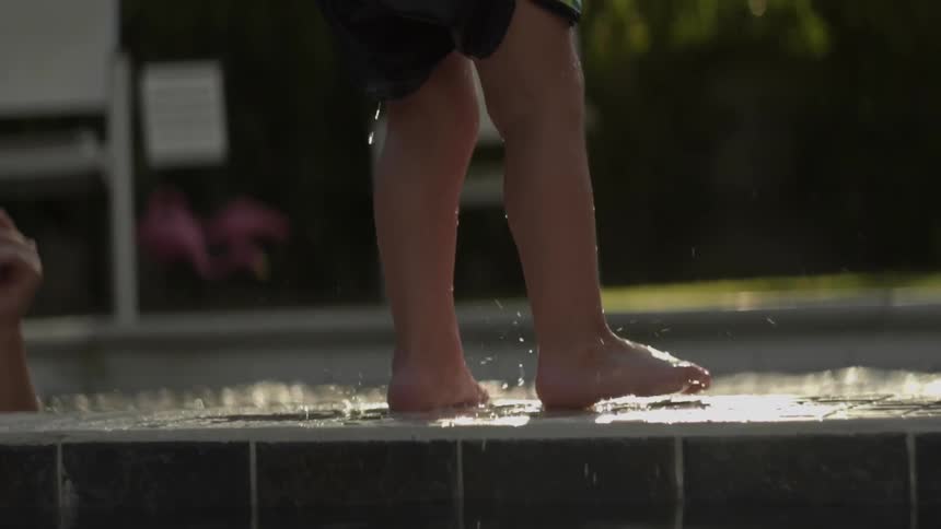 Water drips off of a young boy who just got out of the pool