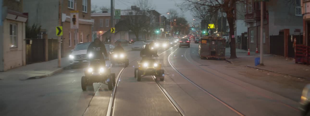 A group of men ride atvs on a city street