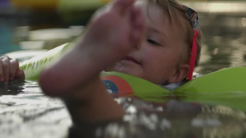 A young boy floats in a swimming pool