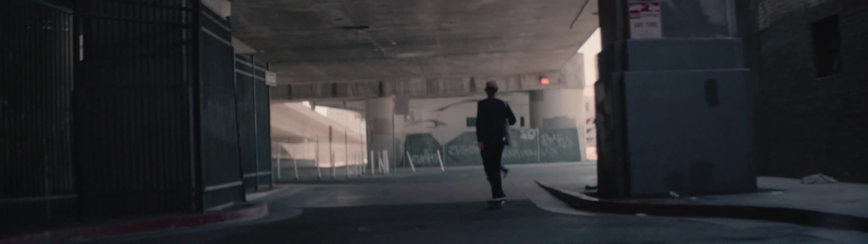 A man rides his skateboard around the corner of the street
