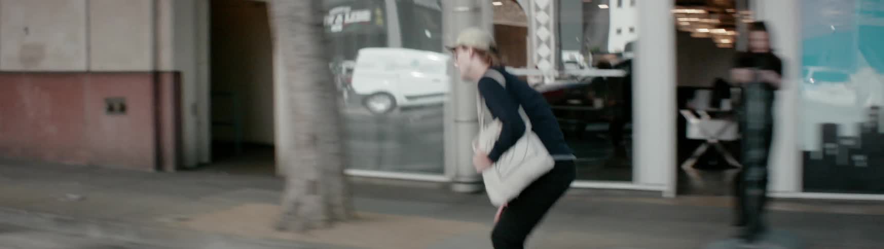 A man rides his skateboard down the sidewalk