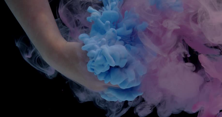 Person's hand submerged in water with different colors of liquid being poured into it