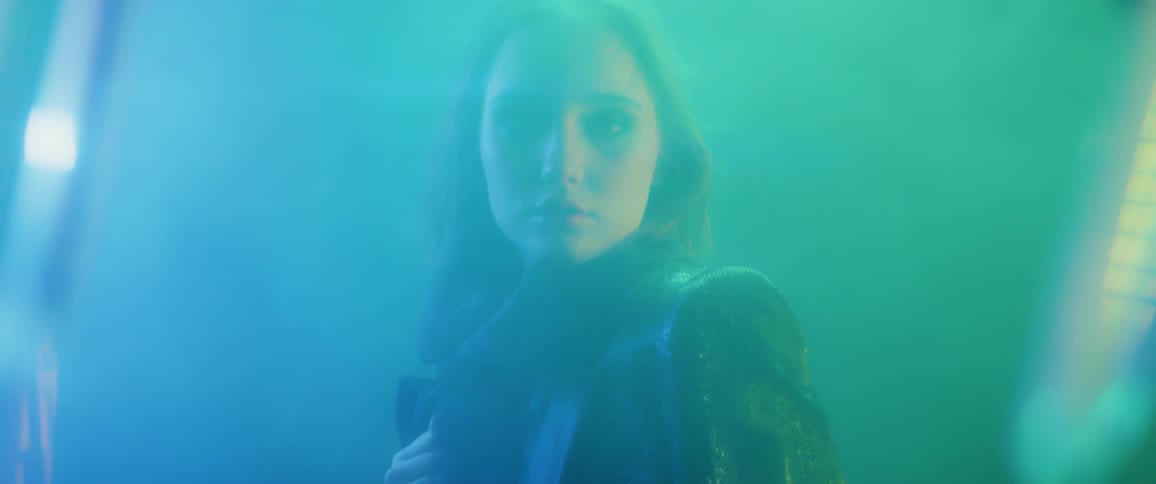 A woman is moving seductively as she stands in a smokey setting