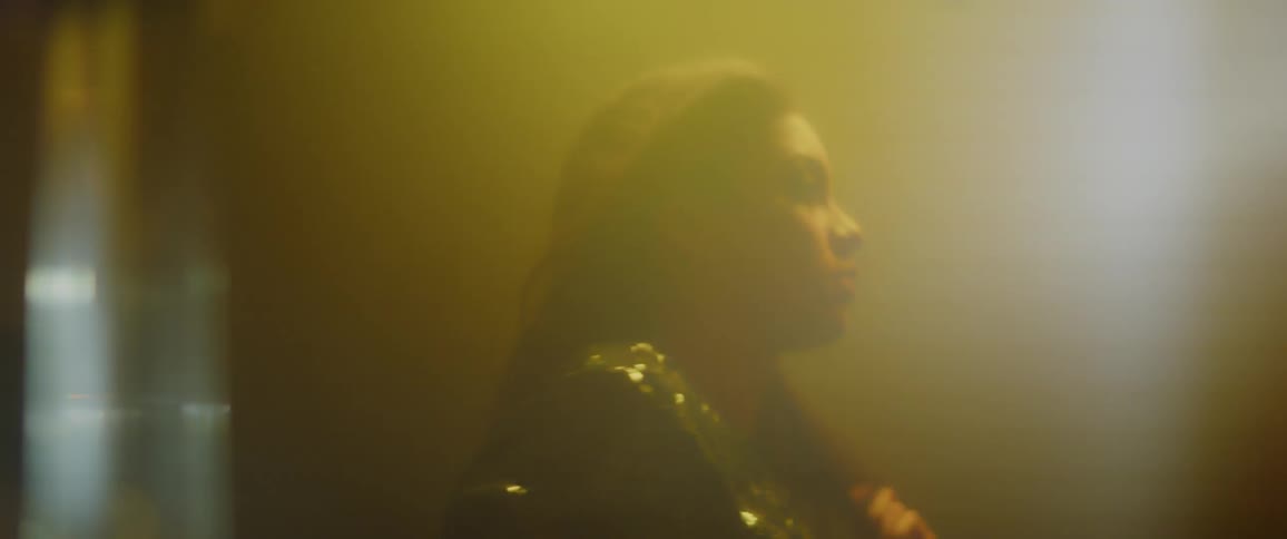 Woman wearing a sparkly shirt illuminated by yellow and red light