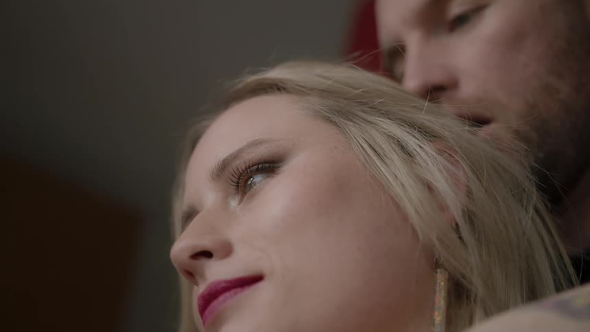 A man is standing behind a woman inside in daylight