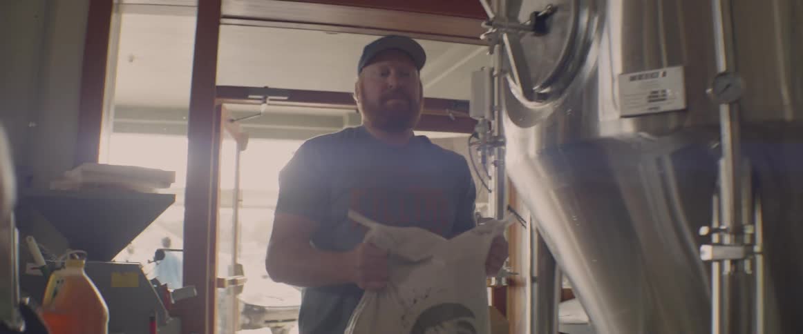 A man picks up a large bag and carries it