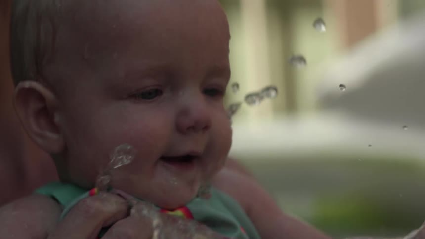 Woman carries a baby as it splashes water