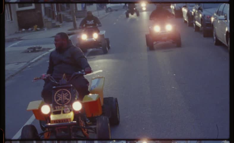 People ride their four wheelers down the street