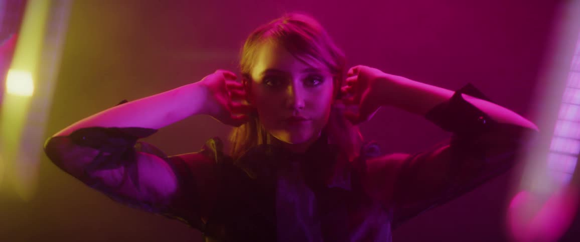 A woman plays with her hair and poses in a foggy room