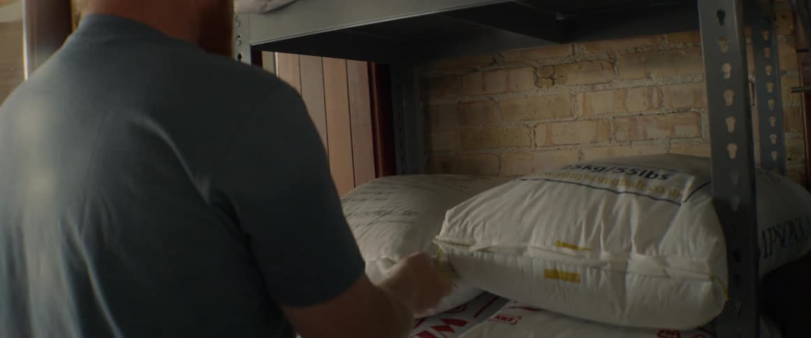 A man stacks bags of grain on shelves
