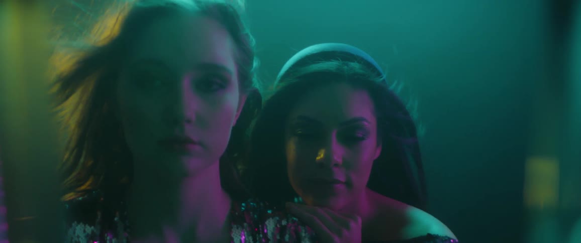 Two women stand in different colored lights