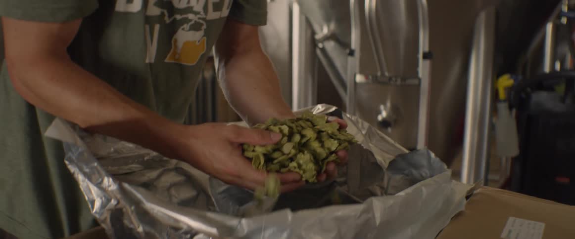 The man picks up some barley from a crate