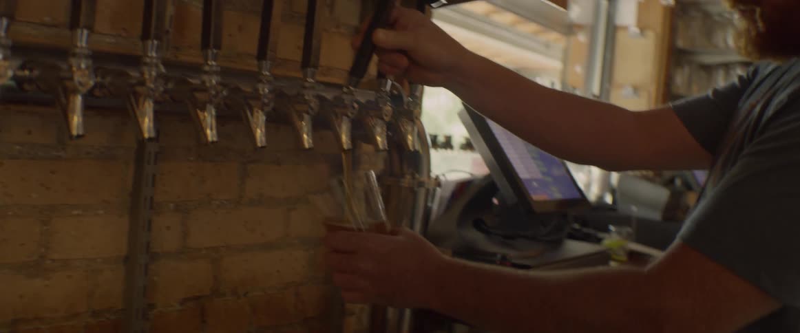 A bartender pours a glass of beer