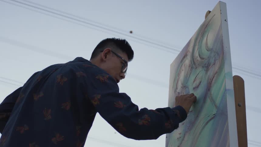Man sketches on a canvas under a cloudy sky