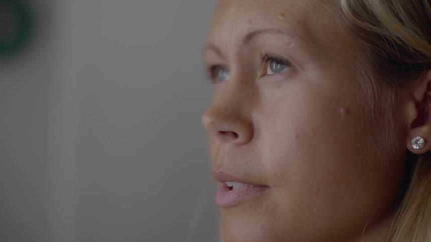 A serious woman with blue eyes reflects on her health while sitting inside.