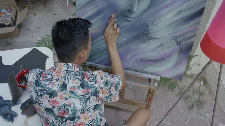 An artist works the paint on a canvas with his fingers