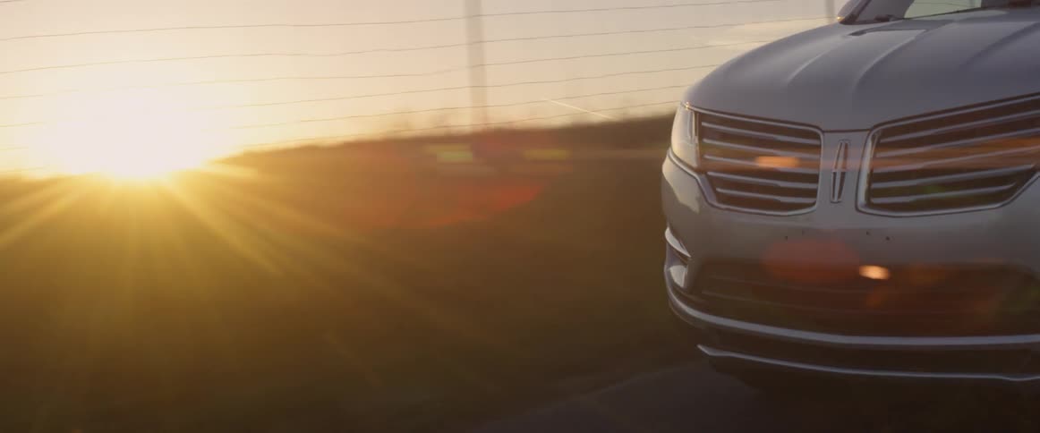 A car drives on a rural road at sunset