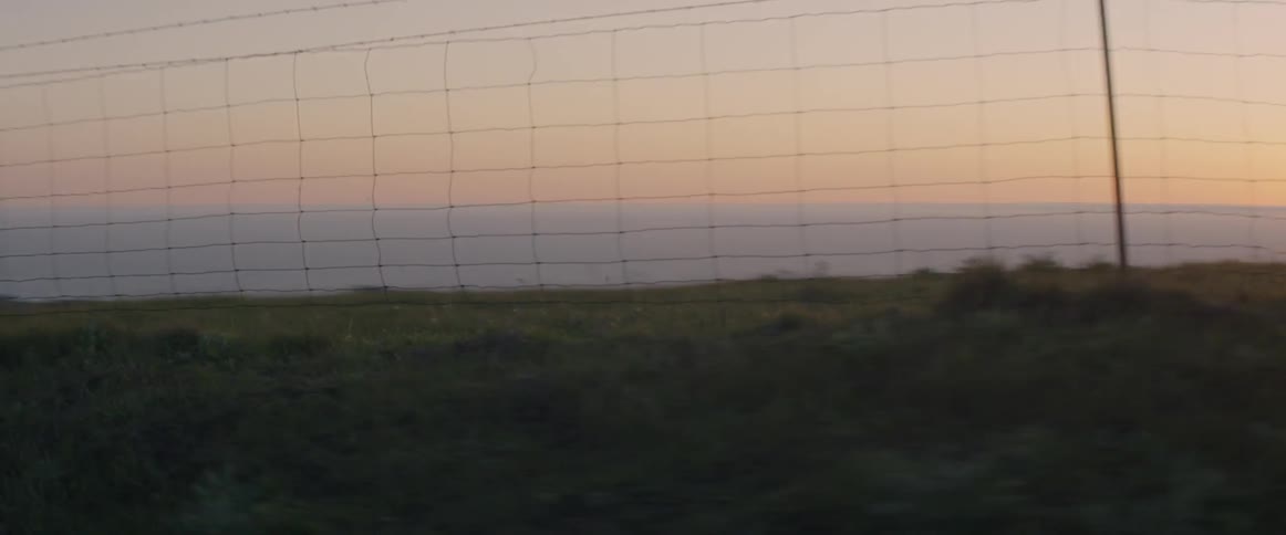 A car drives on a rural road at sunset
