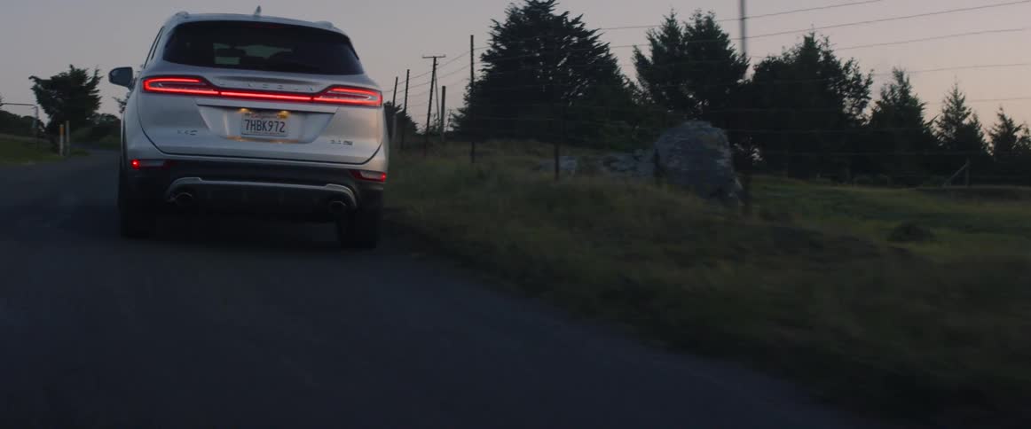 The car drives past the fence at sunset