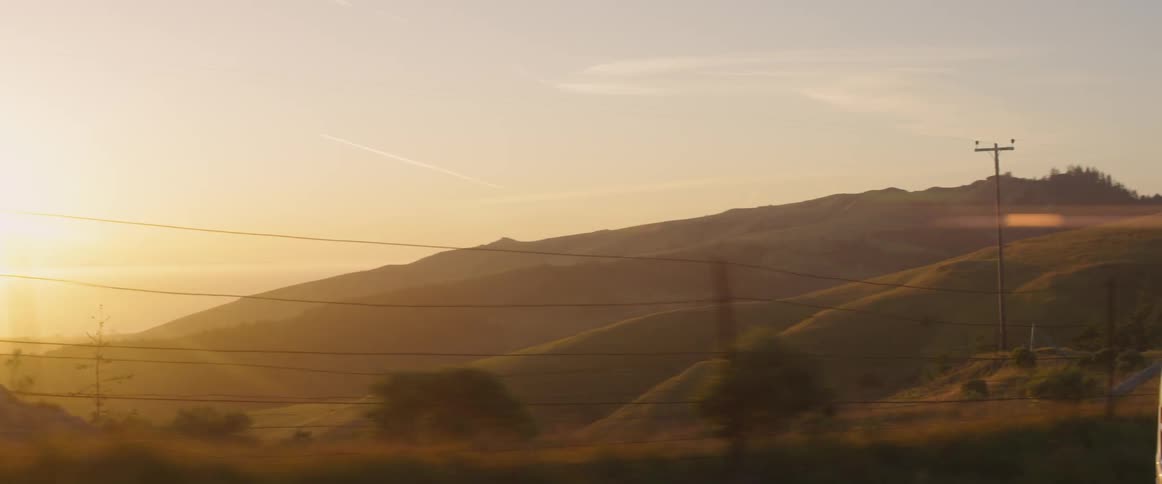 A car is driven on a rural road at sunset