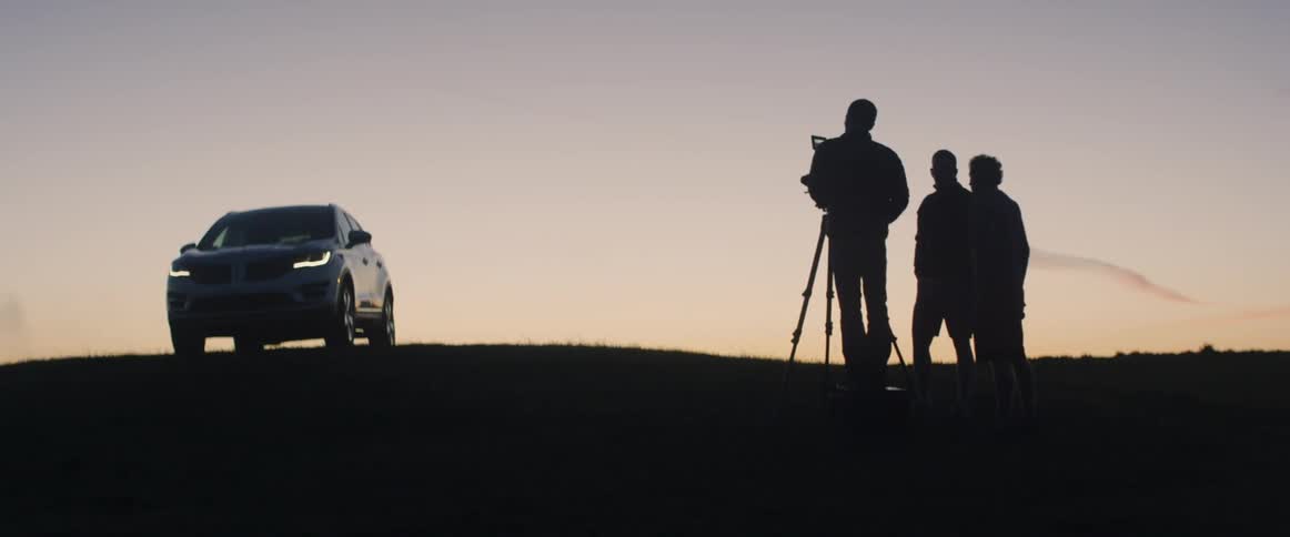 A car is being filmed at sunset on the hill