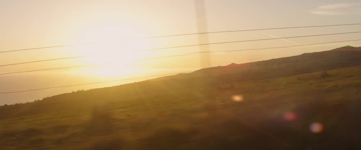 The sun is setting in the cloudy sky by the hills