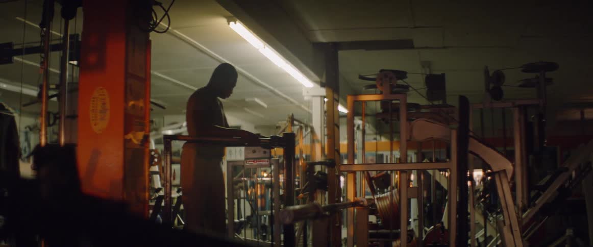 A male athlete is resting as he stands in a gym at night