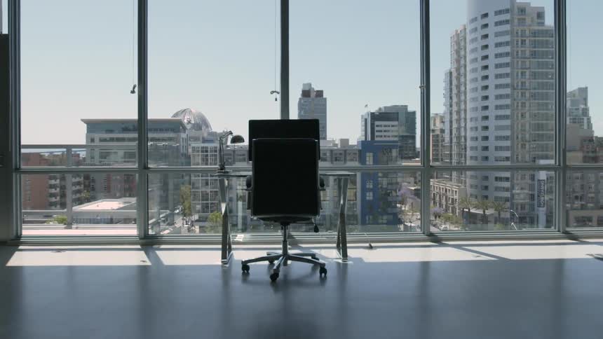 A desk and office chair sit in front of floor to ceiling windows