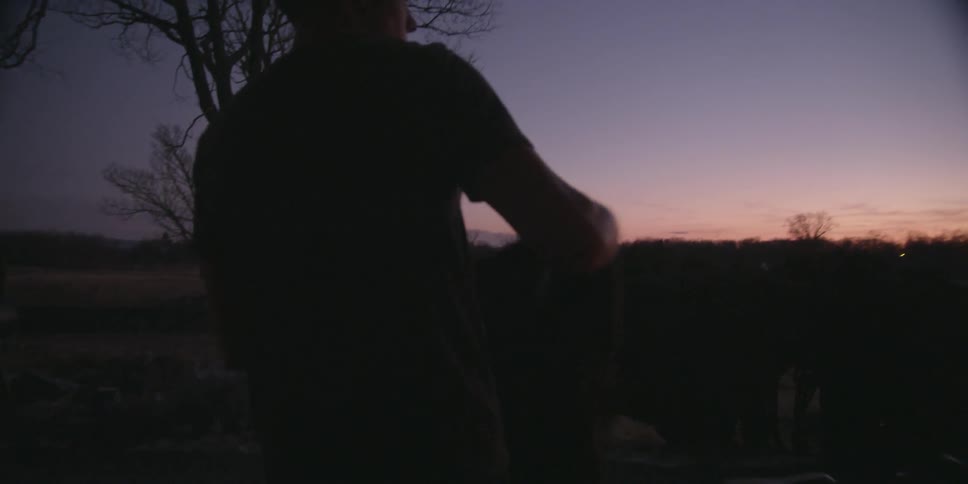 A white male teenager walks out of a house and puts a jacket on outside