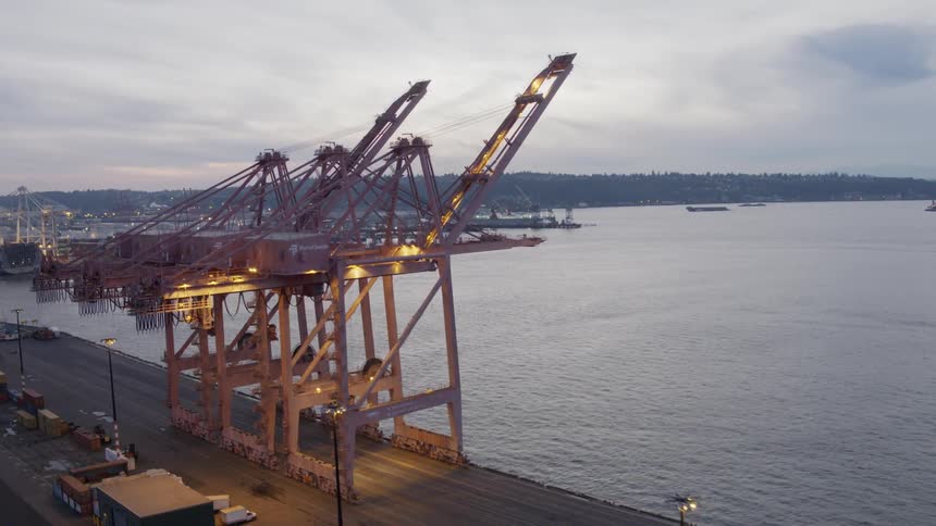 Flying behind lighted container cranes in a shipping yard