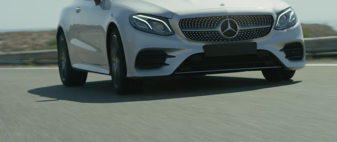 A mercedes being driven on a sunny day