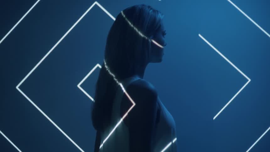 A pattern of lights is moving across a woman standing still in a room