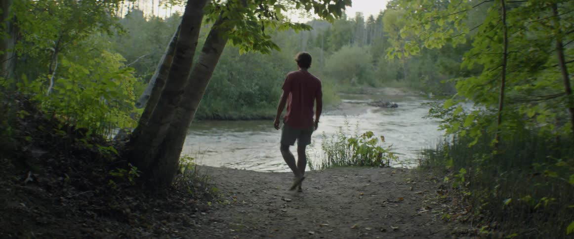 Teenager walks towards a small flowing river