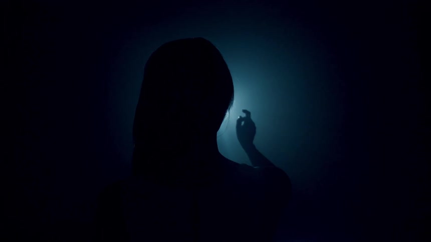 A woman stands in front of a light