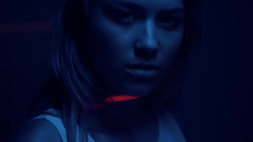 A light shines on a woman's face in a dark room