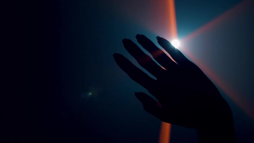 A woman holds her hand in front of a light