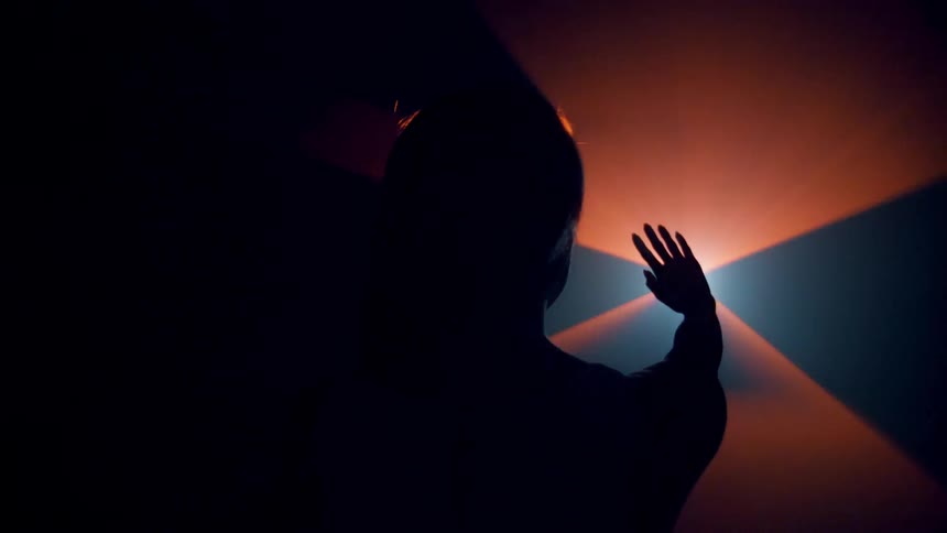 Woman stretches her arm towards a colored light