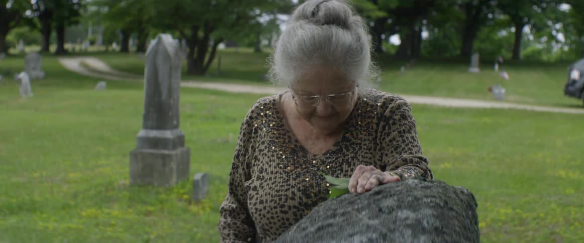 A woman mourns next to a headstone