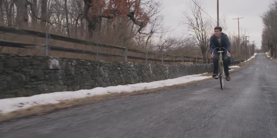 A bicyclist rides down a rural road in the winter