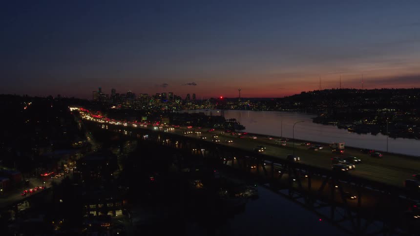 Bright headlights and taillights of moderate traffic flowing across a bridge at dusk